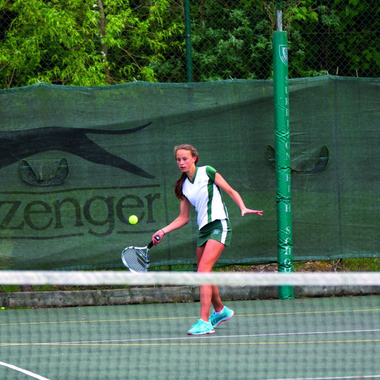 student hitting tennis ball