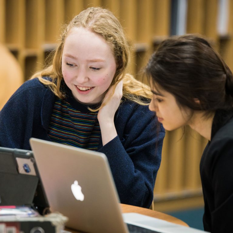 girls sat in a library doing school work