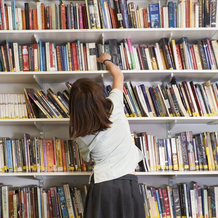 A student picking out a book from the shelf