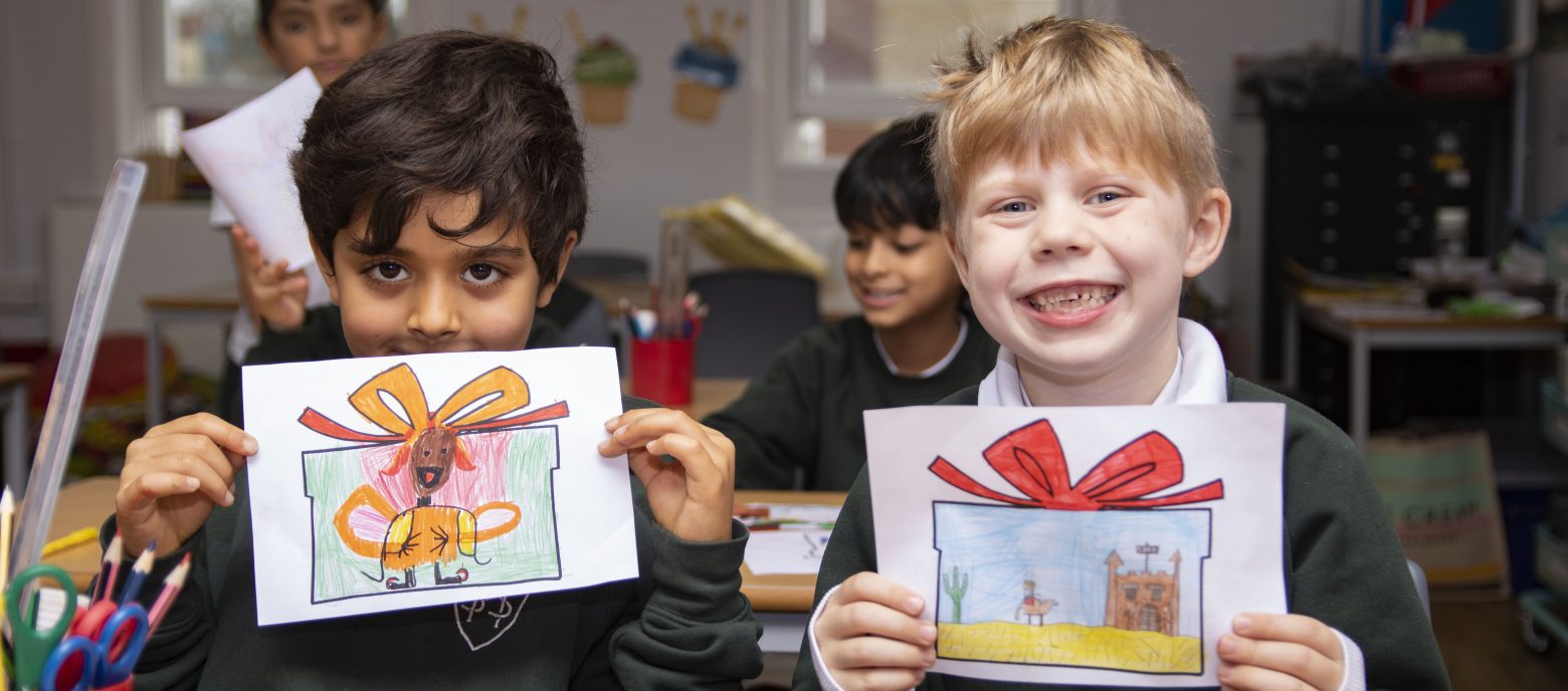 2 students with pictures they have drawn and coloured in