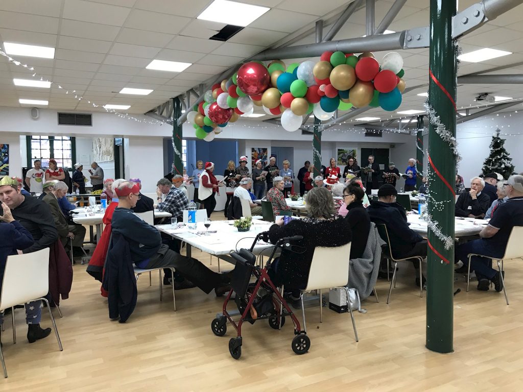 people of all ages surround the tables in surbiton school