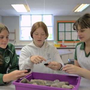 3 students looking and analysing rocks