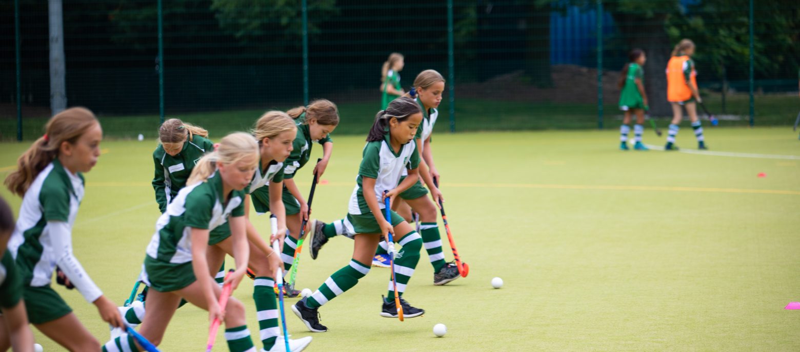 students hitting the hockey balls along the astro turf