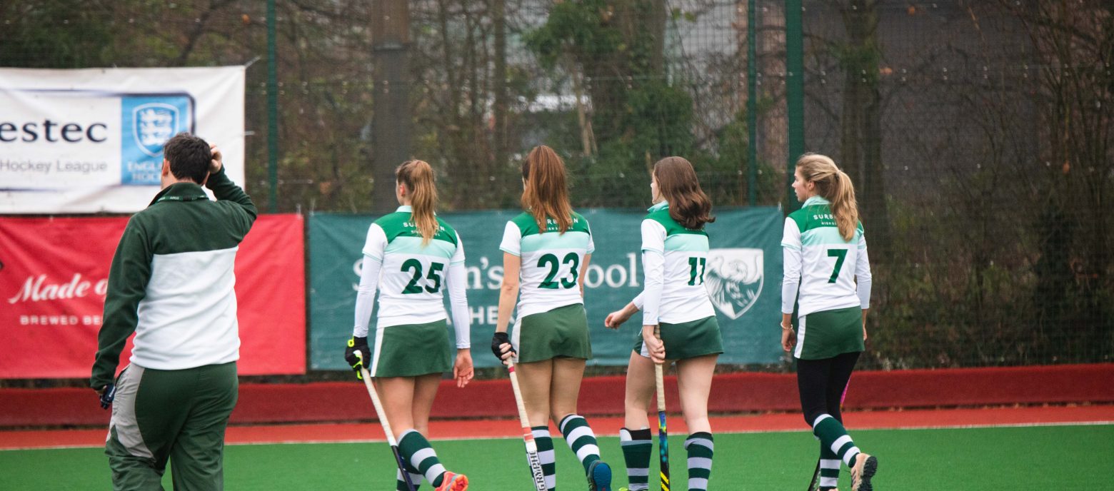 4 hockey players from the school walking along the pitch