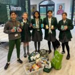 Female students in green uniform holding tinned food.