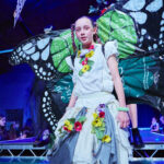 Girl in colourful outfit with butterfly wings on catwalk
