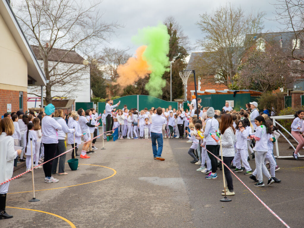 School girls in playground in uniform with colourful paint in air