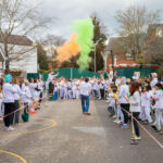 School girls in playground in uniform with colourful paint in air