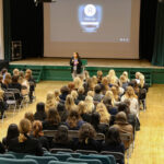 Teacher standing at front of assembly with pupils