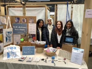 Female students behind stand at tradeshow