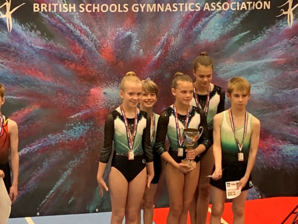 4 children in gymnastics clothes wearing medals