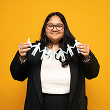 student holding a paper chain of people