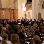 Pupils in uniform standing in church hall