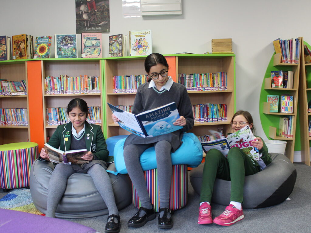 Three girls sitting on bean bags in library reading