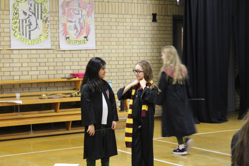 3 girls in a hall dressed in Harry Potter attire 