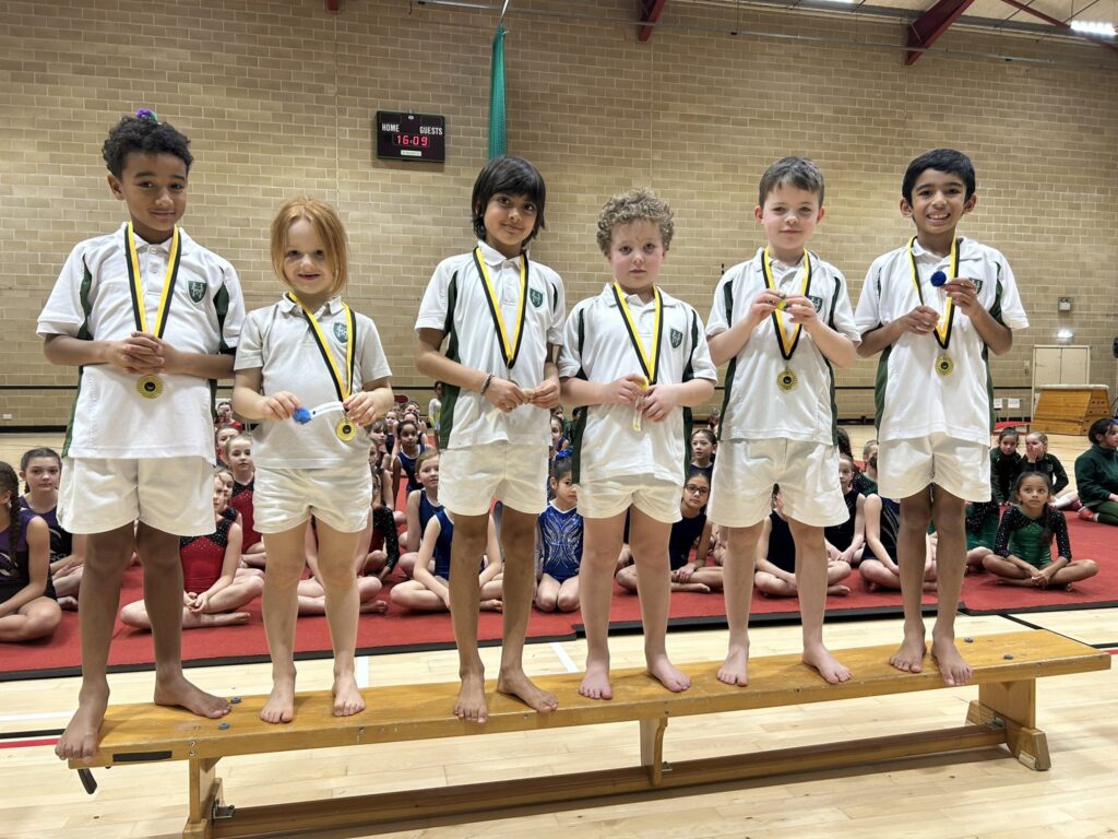 Boys holding Gold Medals standing in a row