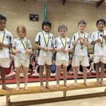 Boys holding Gold Medals standing in a row