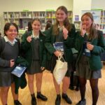 Four girls in uniform smiling at camera