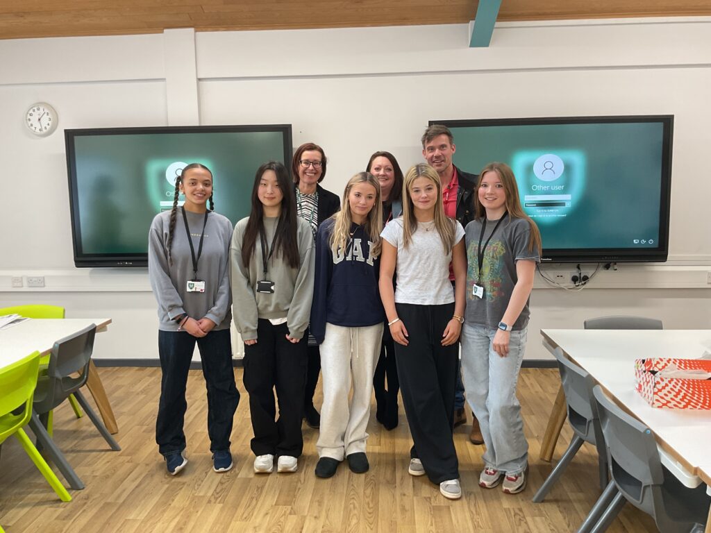 Group of girls standing in front of digital board