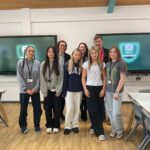 Group of girls standing in front of digital board
